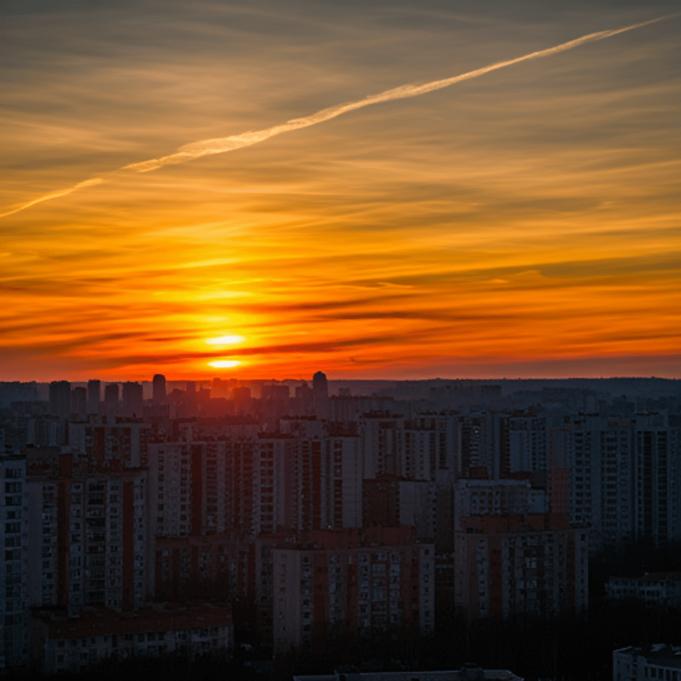 A stunning orange sunset illuminating a city skyline with high-rise buildings silhouetted.